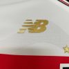 Logo dourado da New Balance em camisa esportiva